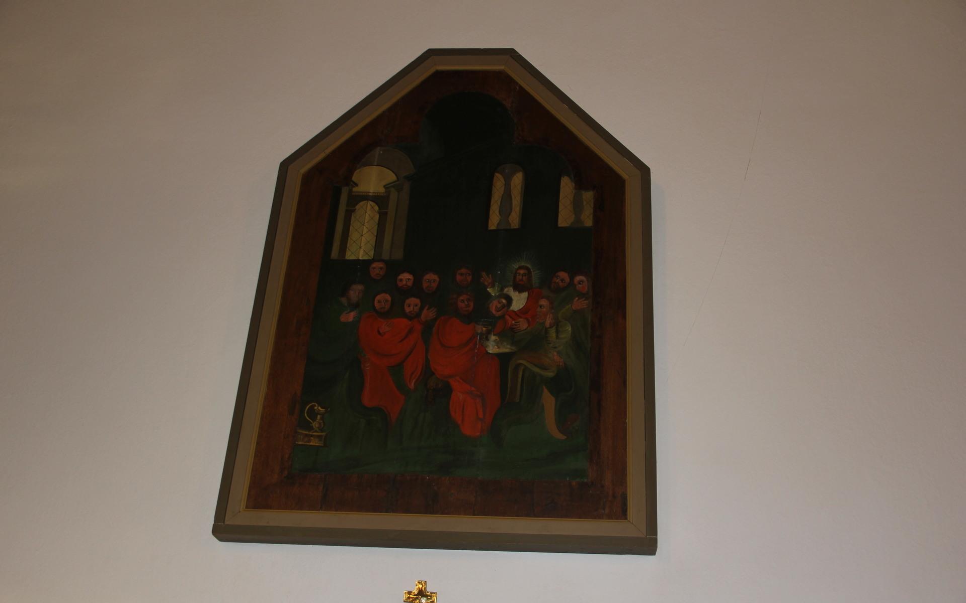 En del av den gamla altartavlan som räddades från branden 1921 hänger nu på en av kyrkans väggar i långhuset.