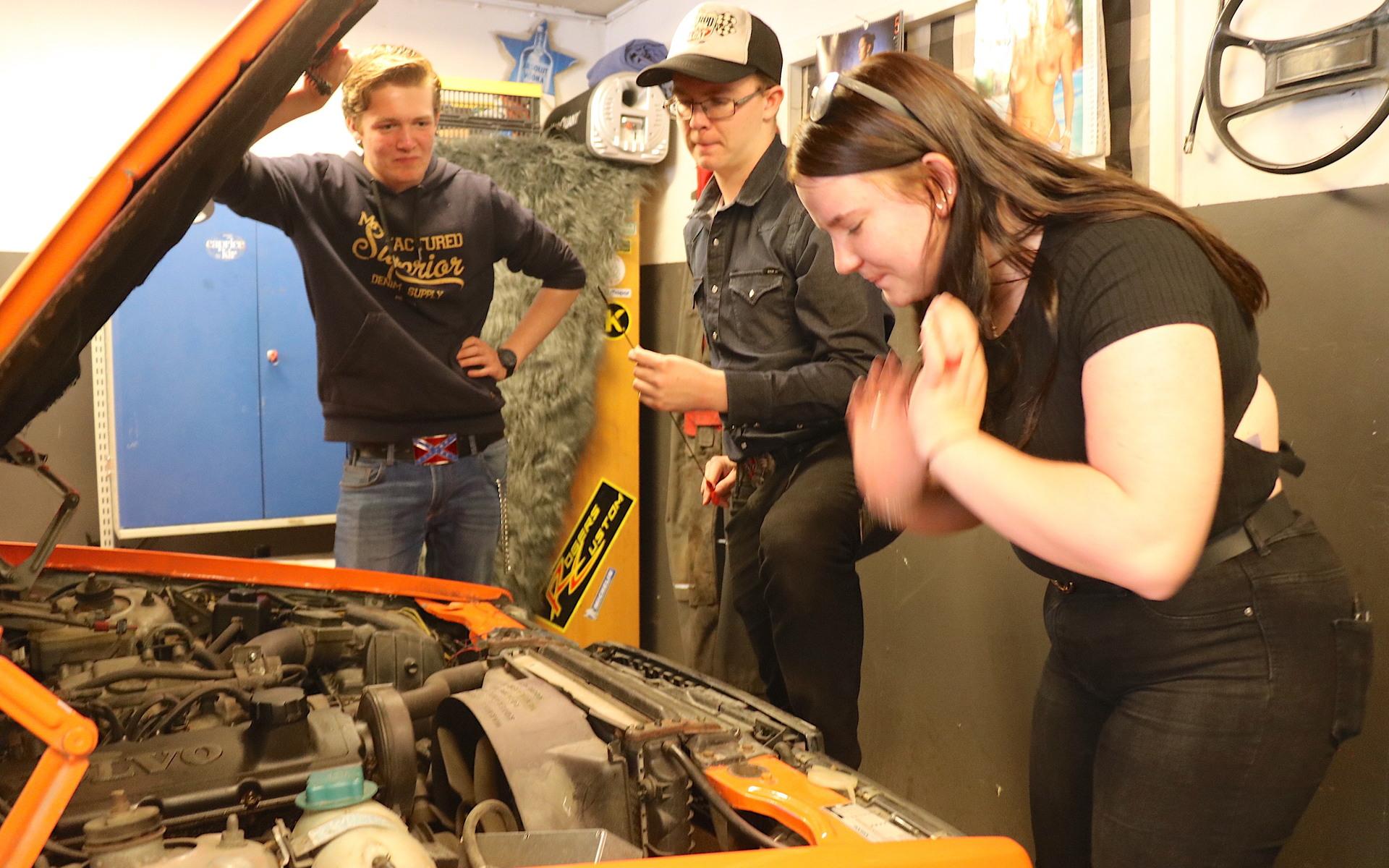 Samuel Persson, William Karlsson och Marija Lukasenko kollar oljan i den a-traktor som en av kompisarna på gården ställt i garaget. 