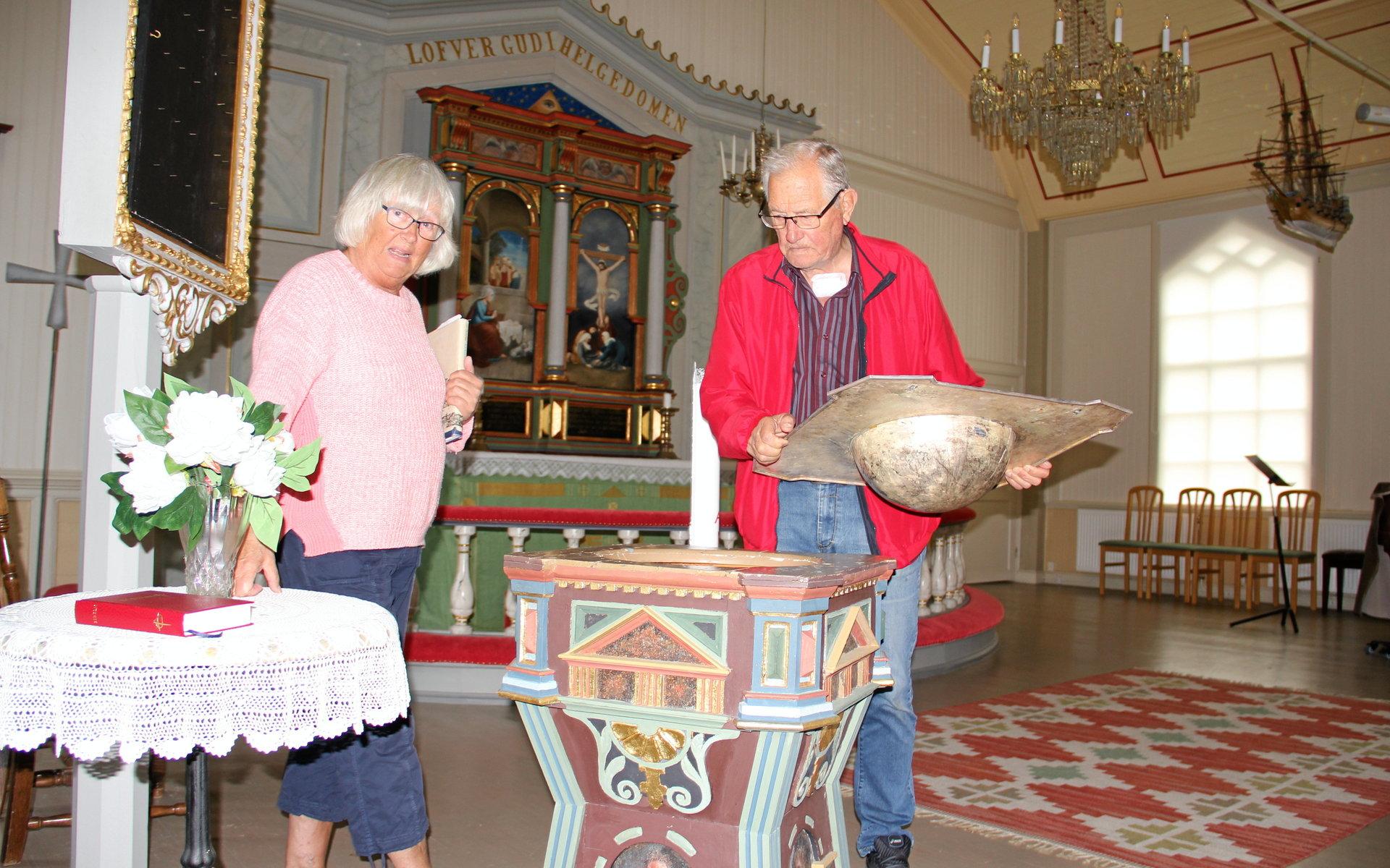 Gunnel Gagner och NIls-Erik Holmström undersöker dopfunten som hängt med från Mollösunds gamla kyrka.
